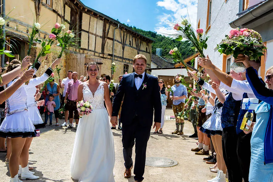 Ein Brautpaar läuft durch ein Spalier von jubelnden Gästen.