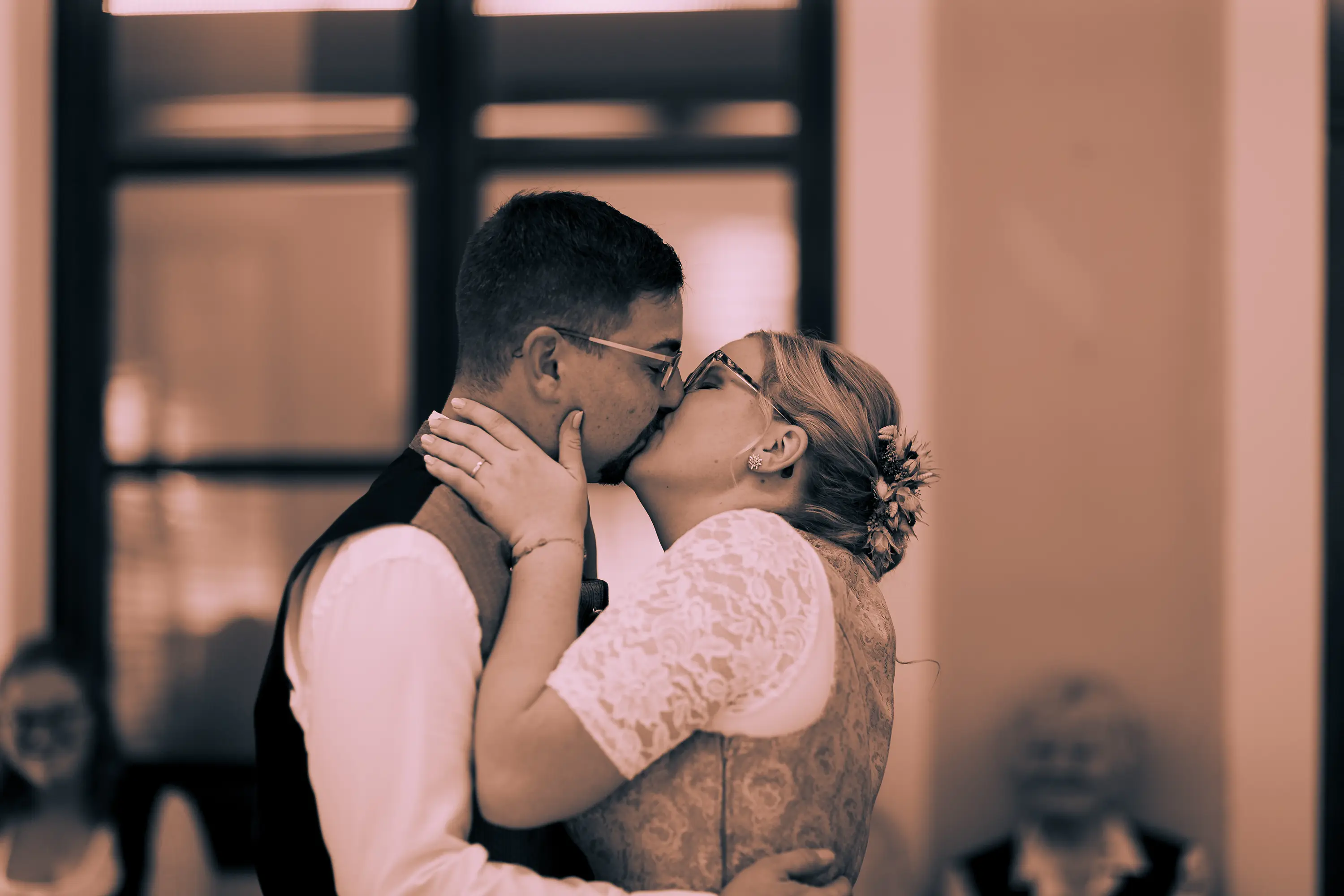 Schwarz-weiß Aufnahme wie sich das Brautpaar nach der standesamtlichen Trauung küsst.