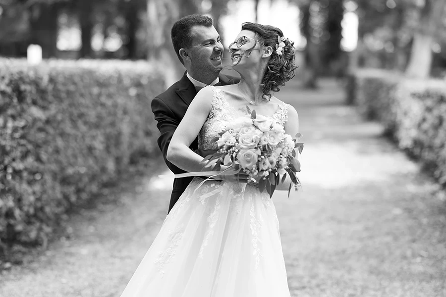 Schwarz-weiß Bild des Brautpaares, der Bräutigam umarmt die Braut von hinten.