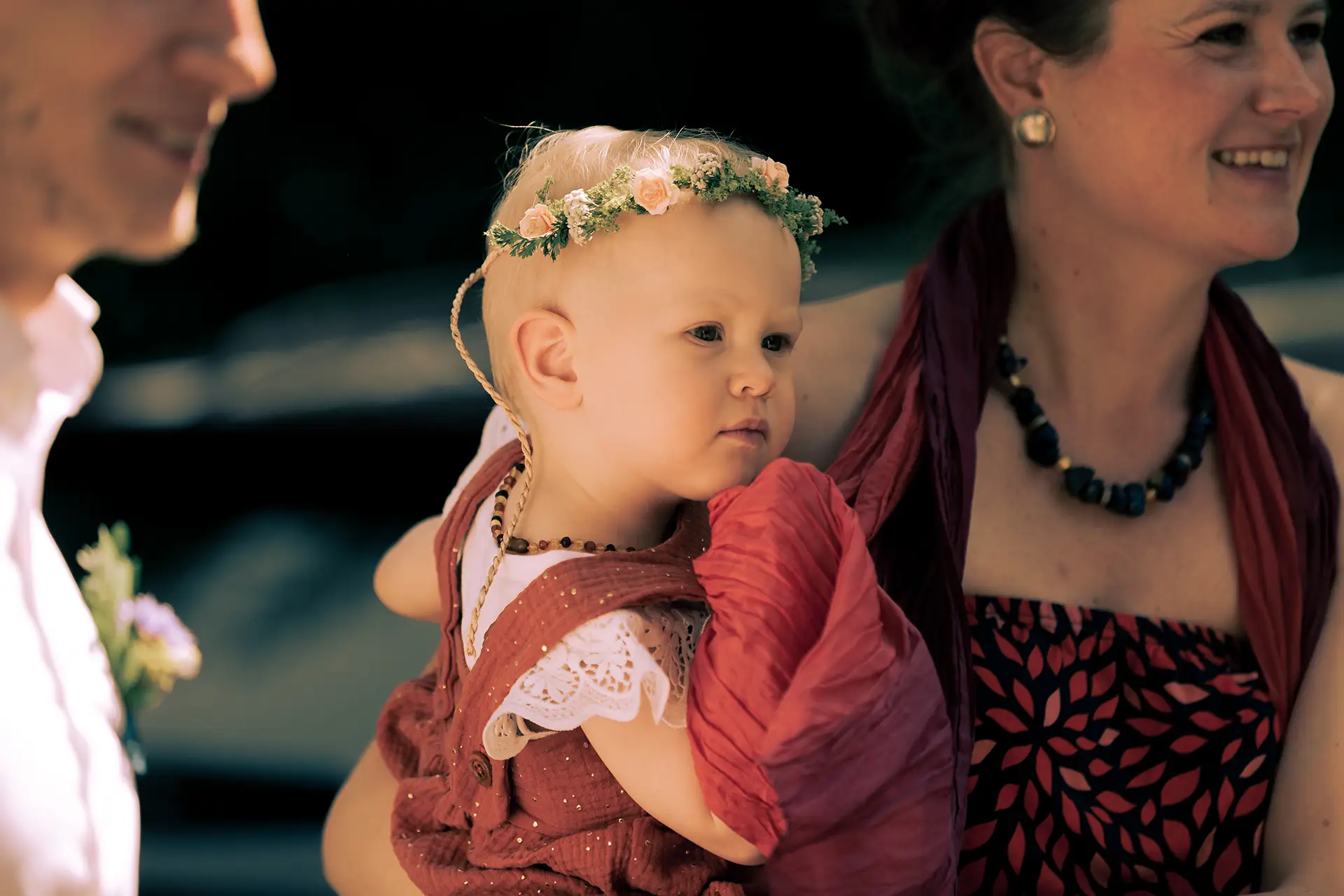 Nahaufnahme eines Babys mit einem Blumenkranz im Haar.