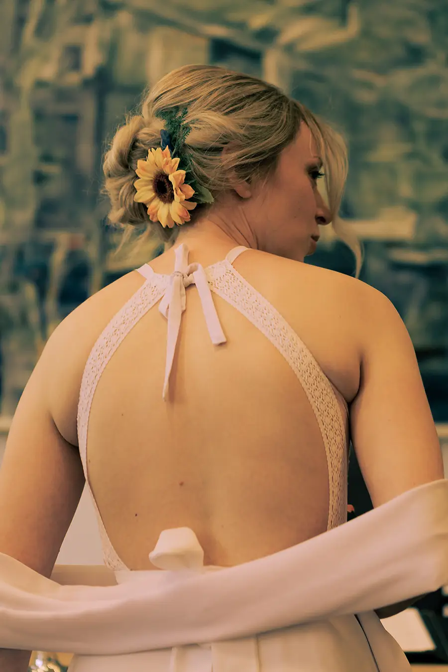 Hochkantaufnahme von der Braut von hinten im Standesamt, sodass man den hinteren Teil ihres Hochzeitskleides sieht.