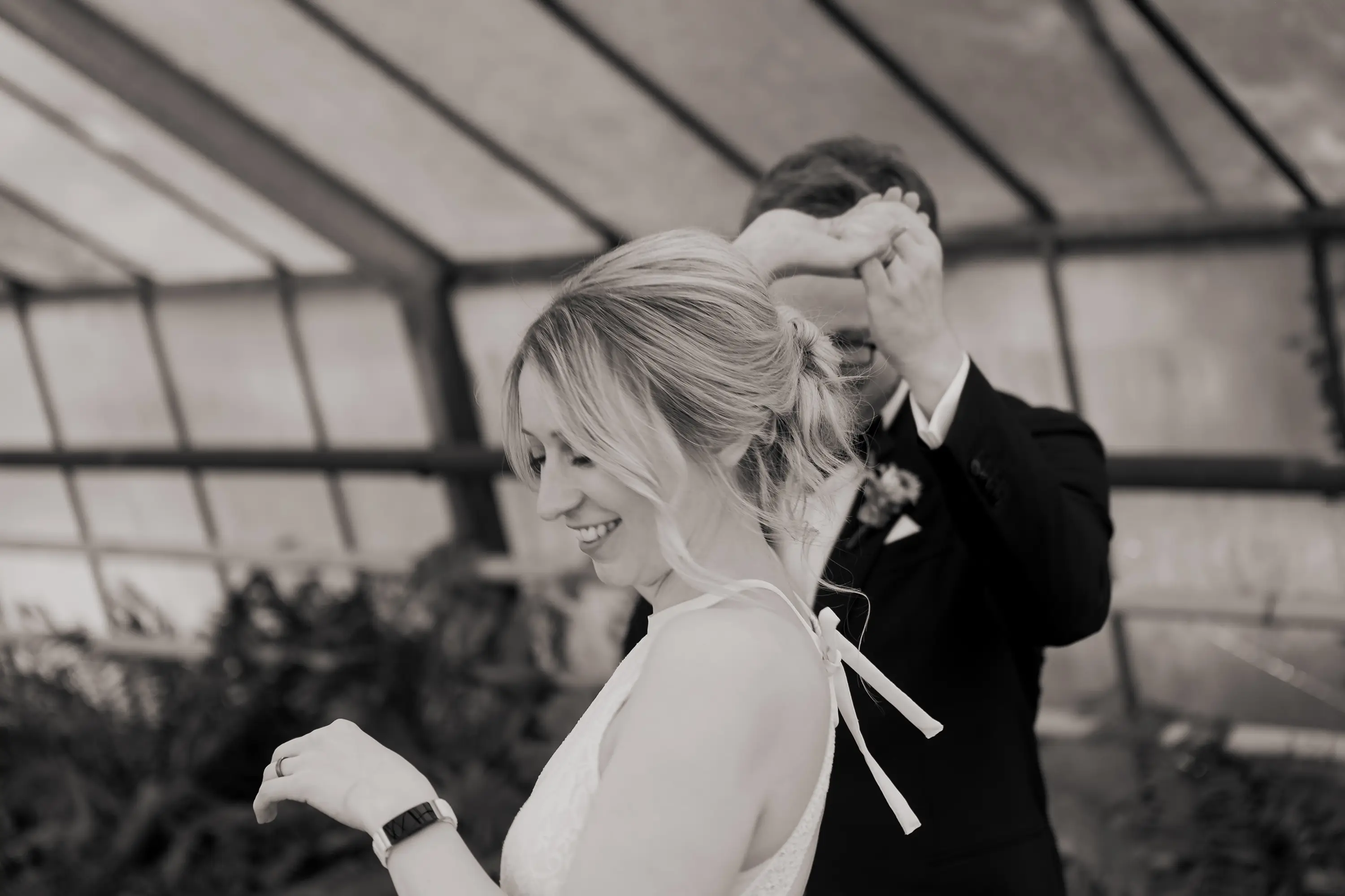 Schwarz-weiß Foto wie das Brautpaar tanzt, dabei ist die Braut im Vordergrund scharf zu sehen und im Hintergrund unscharf der Bräutigam