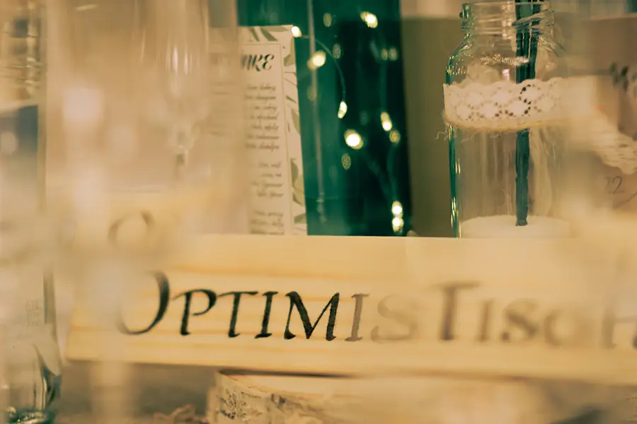 Aufnahme des Holzschildes an einem Tisch mit der Bezeichnung OptimisTISCH.