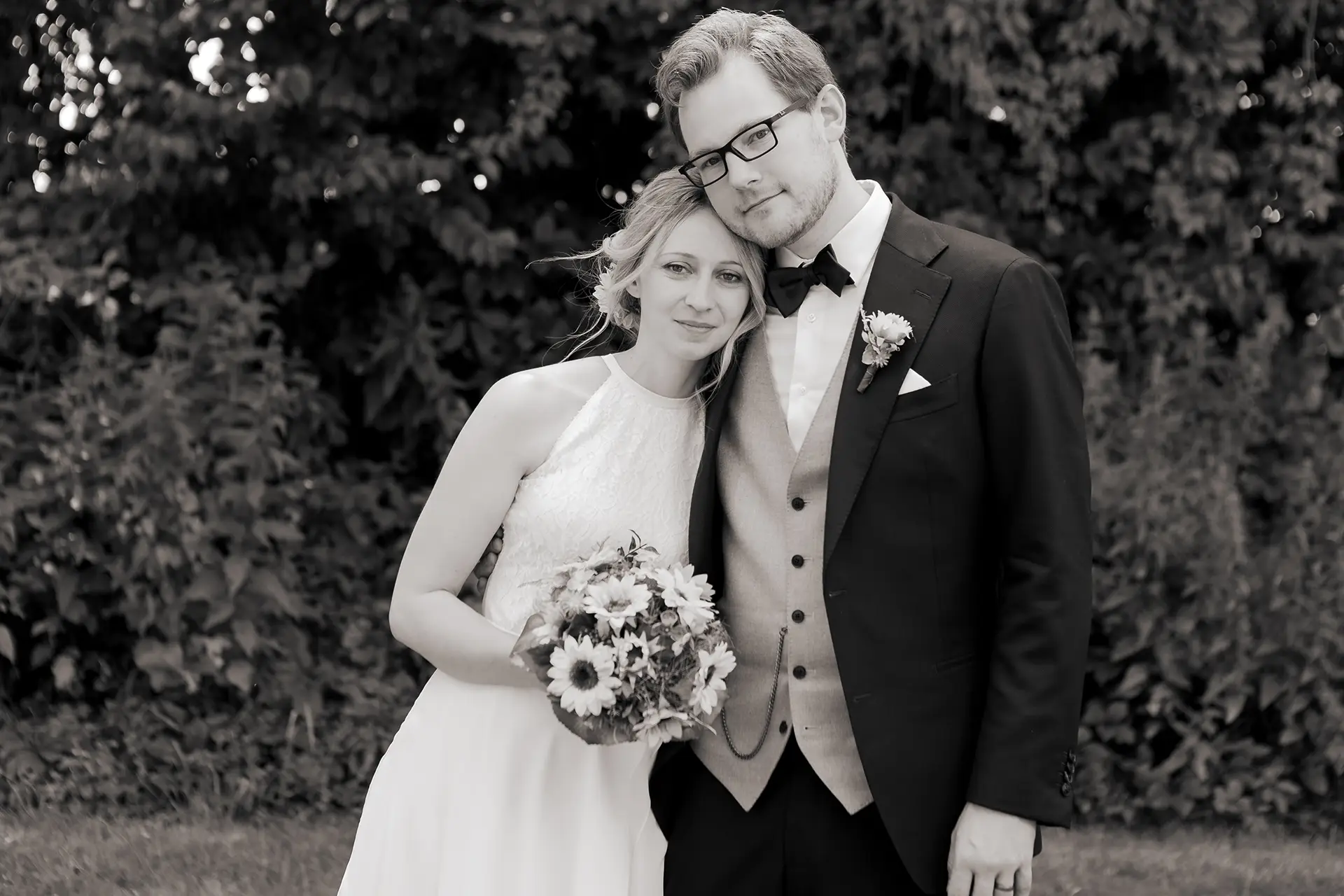 Schwarz-weiß Bild des Brautpaares, das nebeneinander steht und die Köpfe aneinander lehnt.