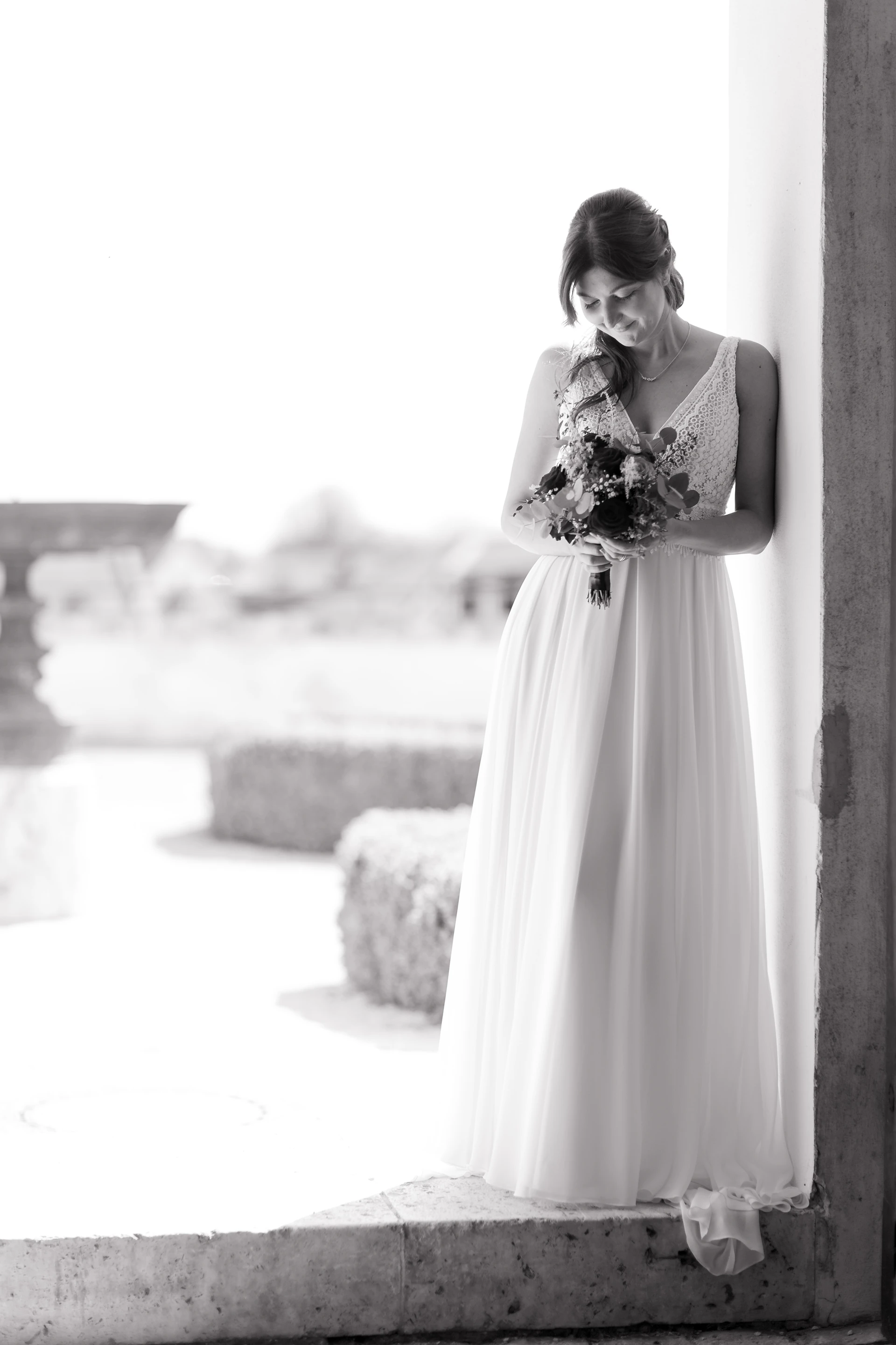 Schwarz-weiß Aufnahme der Braut, die ihren Brautstrauß anschaut.
