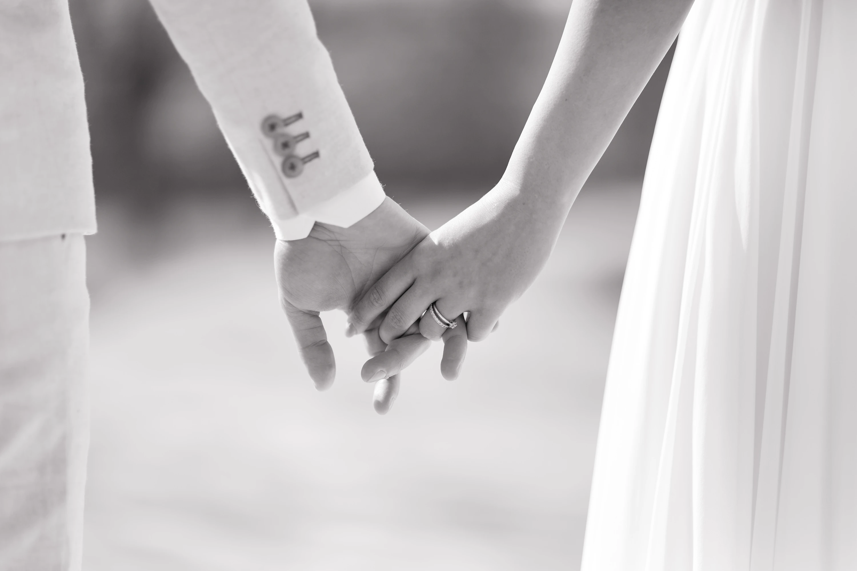Schwarz-Weiß Aufnahme wie das Brautpaar Händchen hält, Nahaufnahme, man erkennt nur die Hände