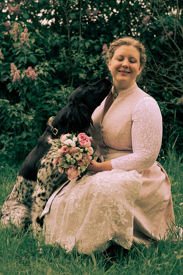 Eine Ganzkörperaufnahme der Braut mit ihrem Hund im Rasen.