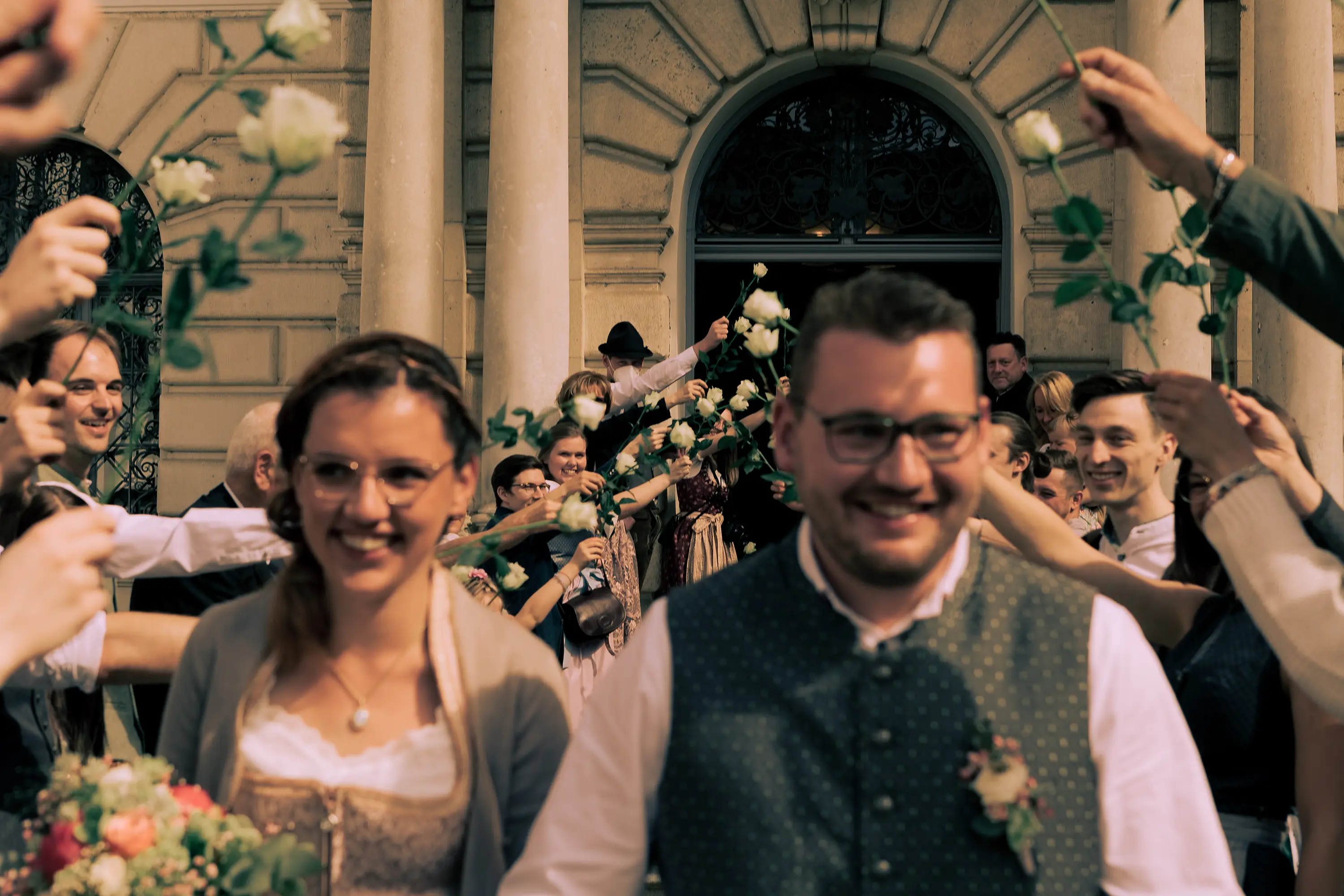 Foto wie die Gäste Spalier stehen, im Vordergrund ist unscharf das Brautpaar erkennbar.